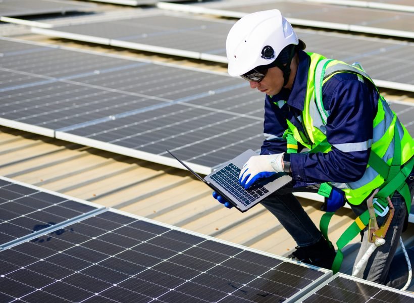 Engineer technician using laptop checking and operating system on rooftop of solar cell farm power plant, Renewable energy source for electricity and power, Solar cell maintenance concept